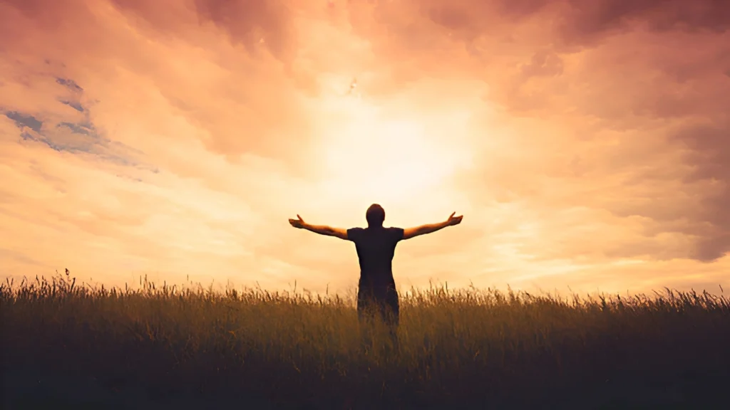 silhouette-of-a-man-of-faith-standing-in-an-open-field-with-arms-outstretched-embracing-a-glowing-sunset-sky-symbolising-spiritual-connection