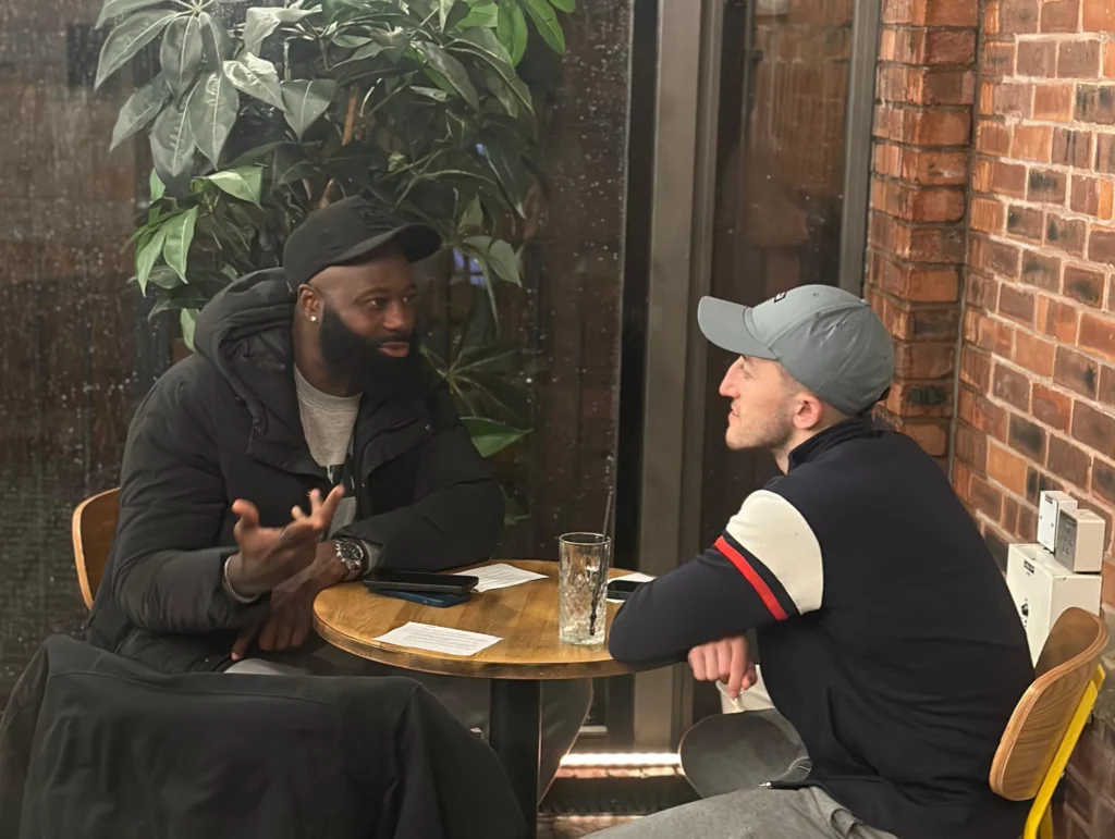 Two-men-engage-in-a-deep-conversation-at-a-small-table-during-an-MPC-event-Season-2-Session-1-Mental-Health