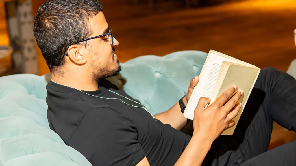 A-member-of-the-Mens-Prosperity-Club-(MPC)-reading-a-book-reflecting-a-moment-of-spiritual-growth-through-quiet-reflection-and-personal-development