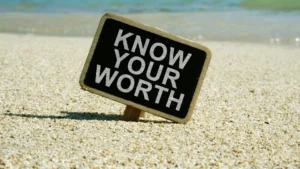 A-sign-saying-Know-Your-Worth-in-the-sand-symbolizing-The-Psychology-of-Money-and-personal-value
