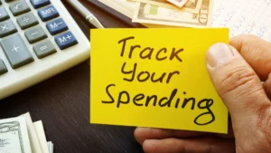 Post-it-note-that-says-Track-Your-Spending-next-to-money-and-calculator-Tracking-spending-to-improve-money-mindset-for-men-in-their-20