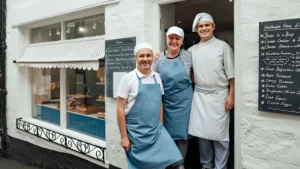 Small-bakery-owners-standing-outside-shop-smiling-representing-Small-Business-Cash-Flow-success