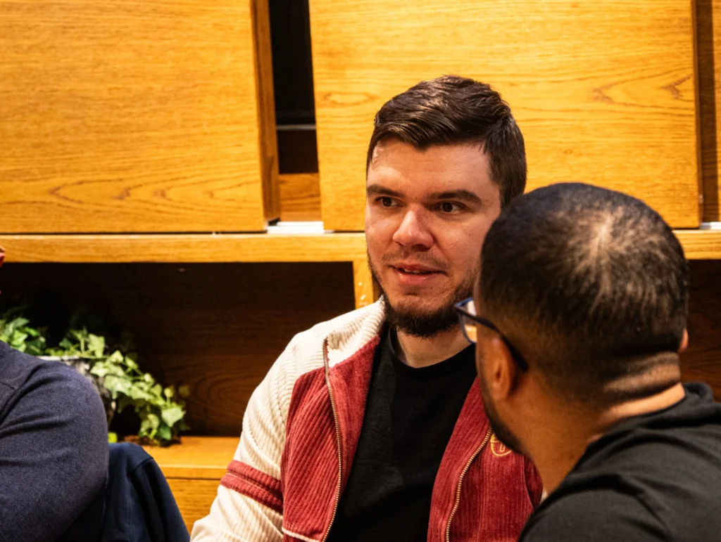 A-man-in-a-red-jacket-and-another-person-engaging-in-a-conversation-in-a-Health-&-Fitness-club-1