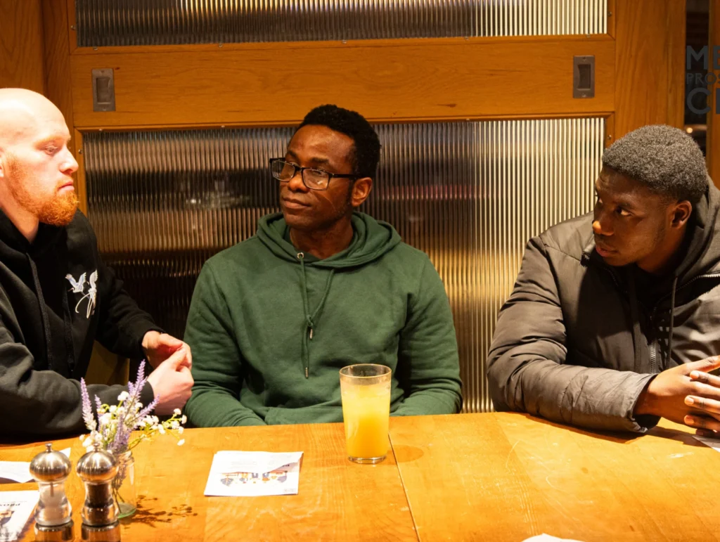 Three-men-sitting-at-a-table-in-a-Health-&-Fitness-club,-one-holding-a-drink,-in-a-deep-conversation-1