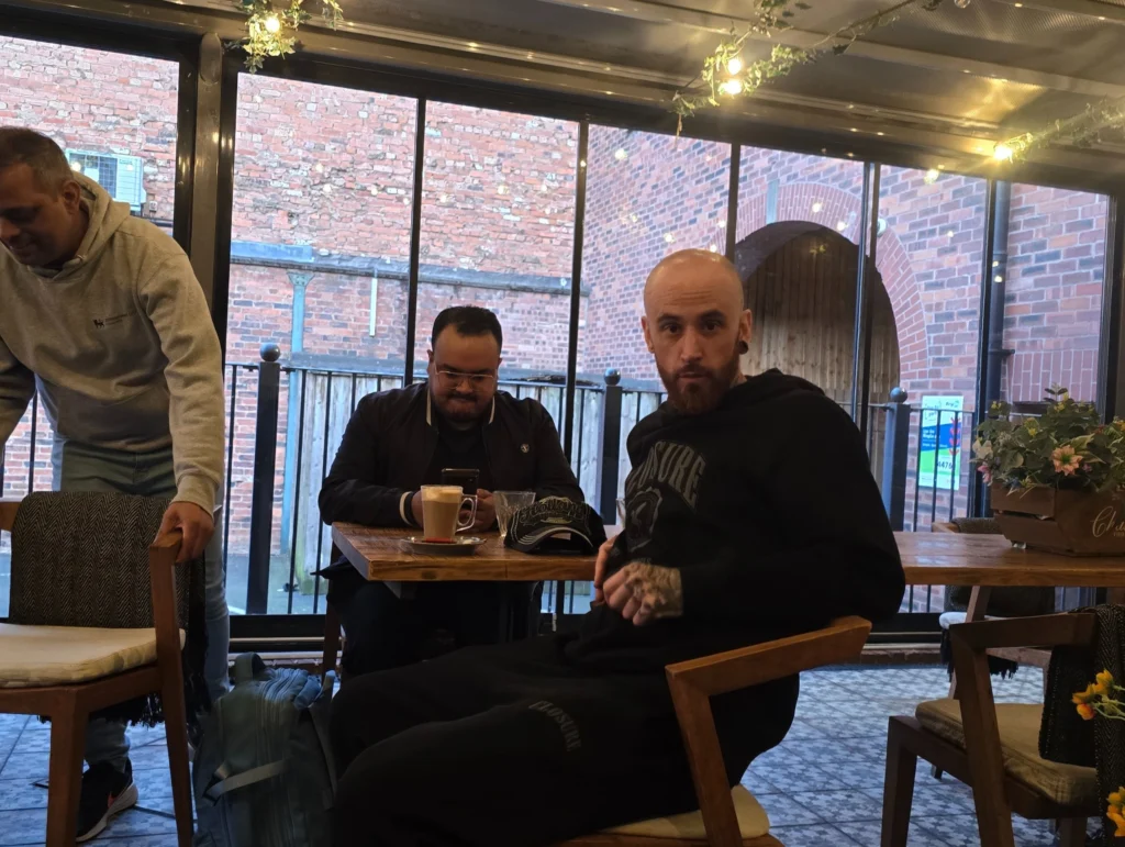 Two-men-sitting-at-a-table-in-a-cozy,-casual-restaurant-with-a-coffee-and-phone-in-front-of-them