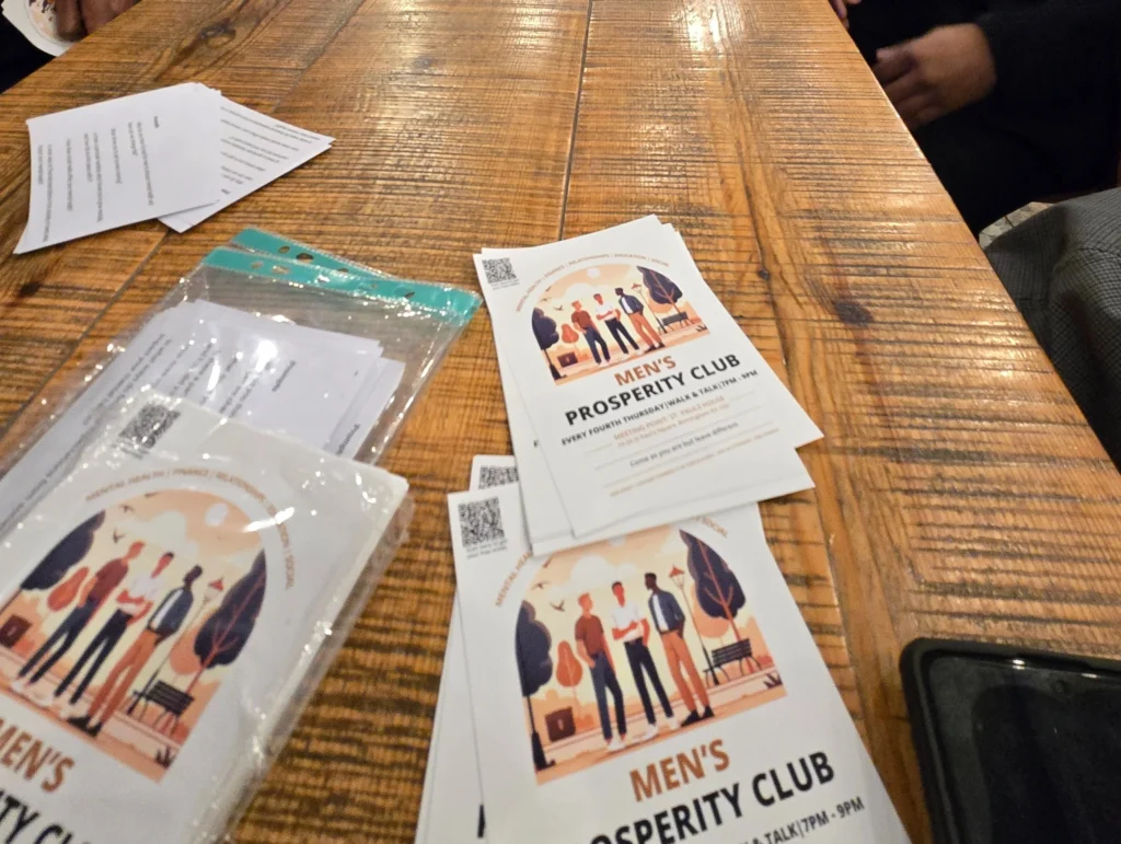 Close-up-of-Men’s-Prosperity-Club-flyers-on-a-table-promoting-mental-health-awareness-and-community-support.