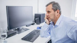 Man-reflecting-at-desk-combating-imposter-syndrome-at-work