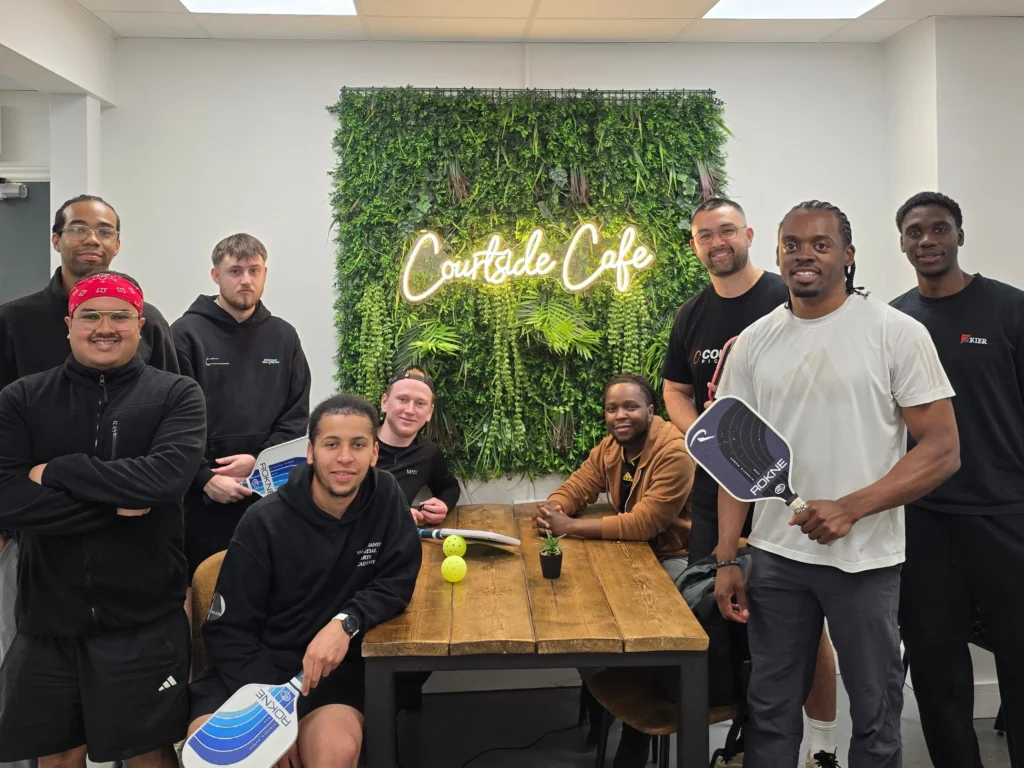 group-photo-at-the-pickleball-event-with-players-holding-paddles-and-posing-at-courtside-cafe
