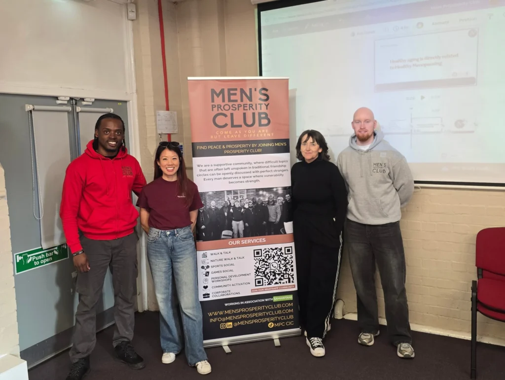 iwd-workshop-spotlight-on-womens-health-pd-workshop-team-photo-beside-mens-prosperity-club-banner